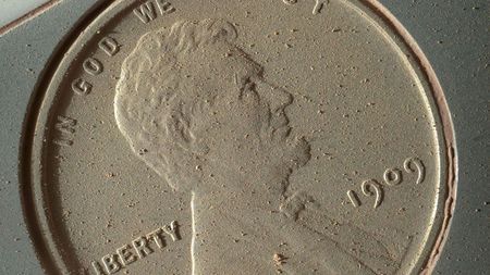 A close-up of the heads side of a penny covered in Mars dust. 